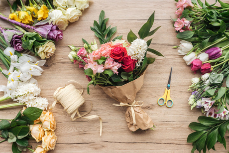 ramo de flores en envoltorio de papel y tijeras sobre superficie de madera.jpg